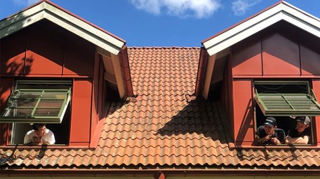 Flera elever står och tittar ut från sitt fönster på skolans elevboende.