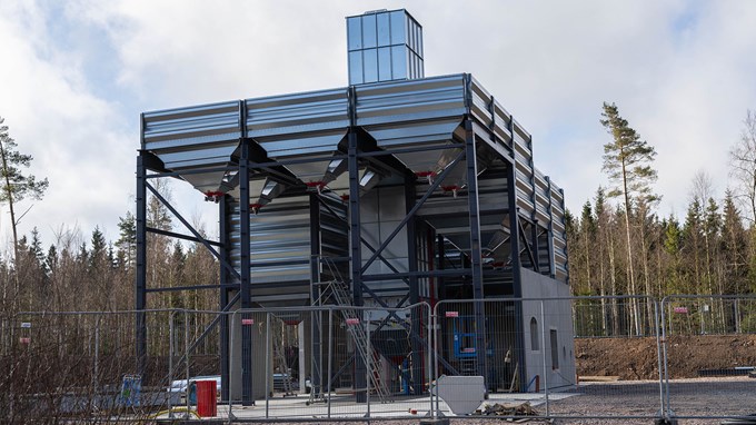 En hög grå byggnad sträcker sig upp mot en blå himmel.