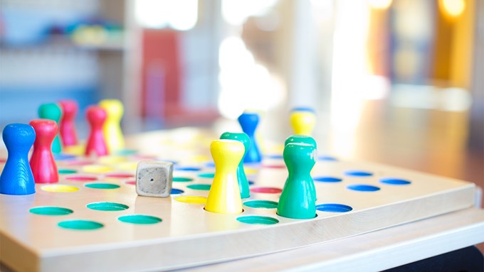 Närbild på fiaspel i trä, men spelpjäser i blått, rött, gult och grönt.
