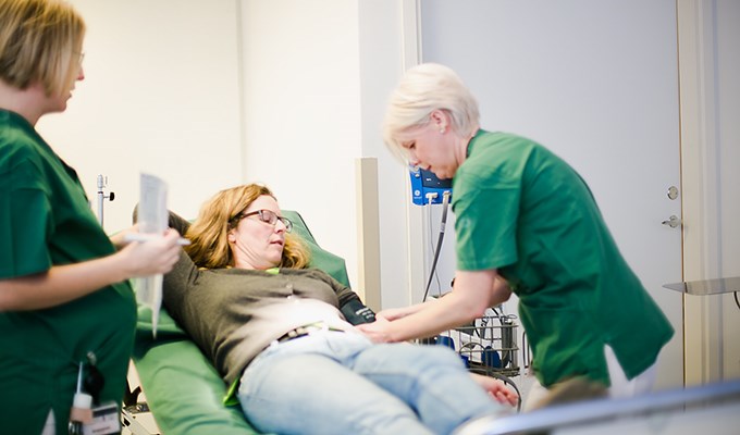 Kvinnlig sjuksköterska undersöker kvinnlig patients blodtryck.