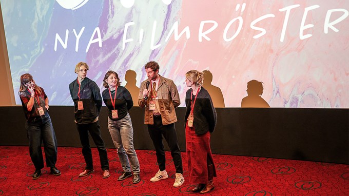 Människor samtalar framför en biografduk. 