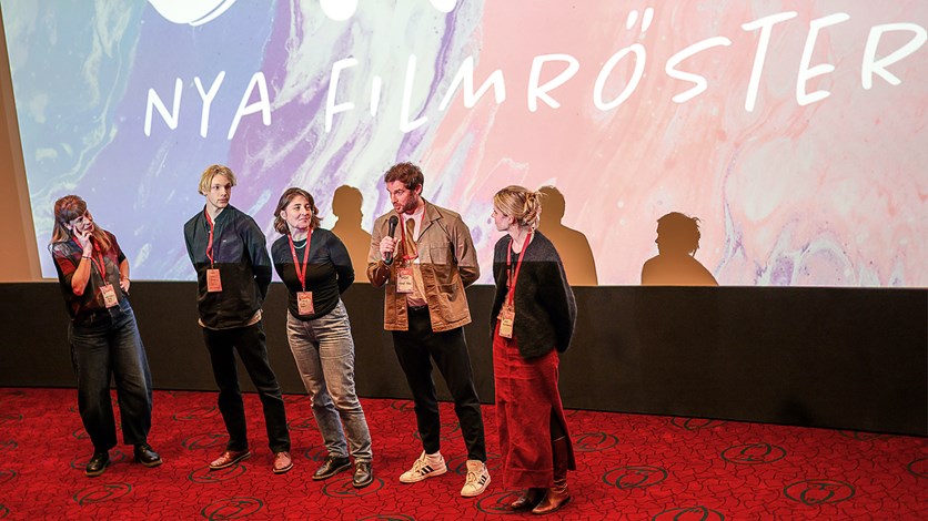 Människor samtalar framför en biografduk. 