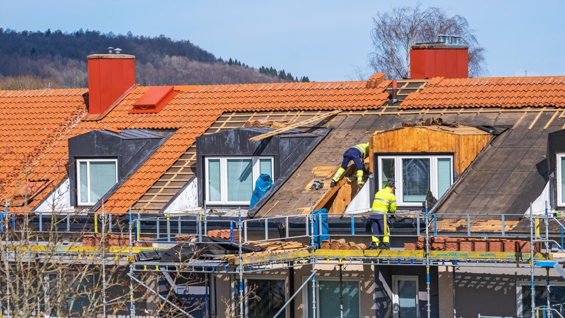 Byggarbetare som byter tak på ett bostadshus.