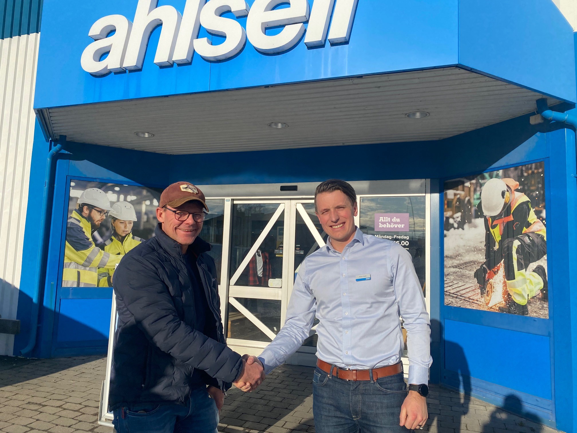 Håkan Jarl från Åtebruka och Anton Hultin från Ahlsell tar i hand utanför Ahlsells butik i Jönköping en solig dag.