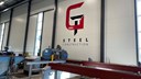 GT Steels produktionslokal, en vit vägg med loggan på väggen och stålbalkar.