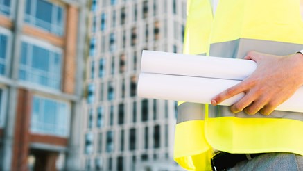 Man i varselväst med byggnader i bakgrunden.