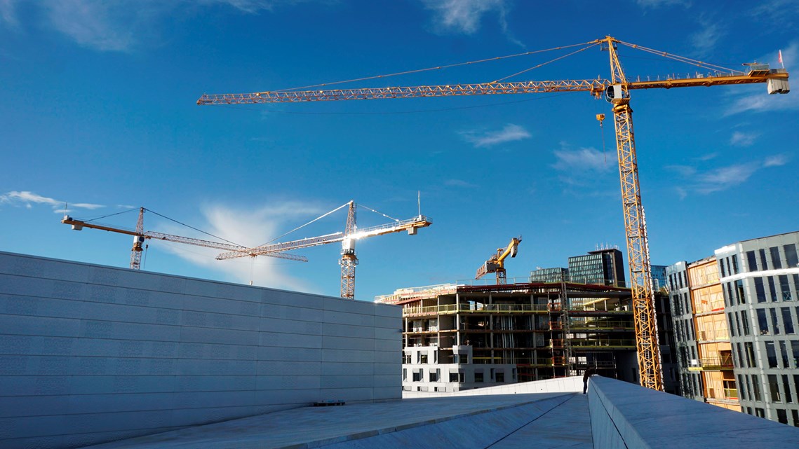 Byggprojekt med flera byggkranar i soluppgång.