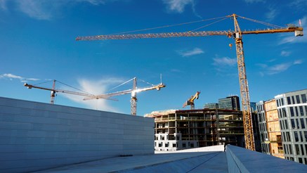 Byggprojekt med flera byggkranar i soluppgång.