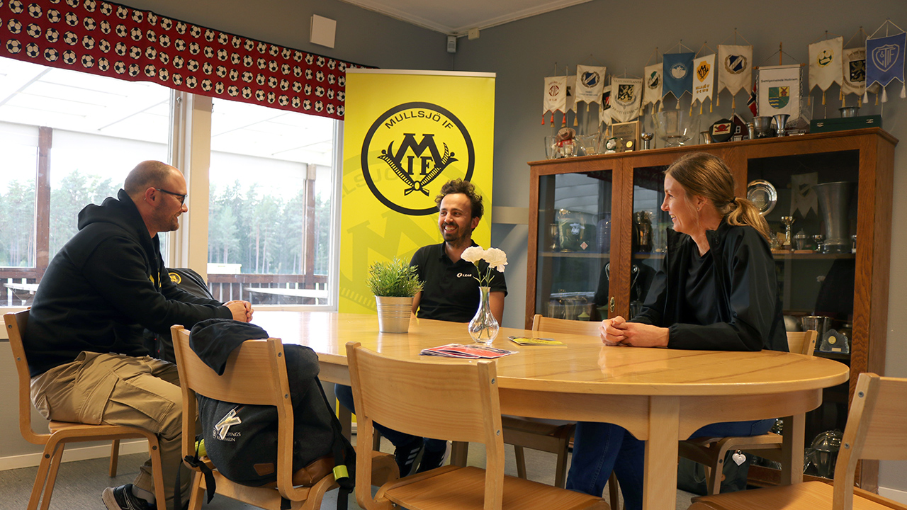 Emil, Jakob och Emma i samtal runt ett bord i klubbstugan.