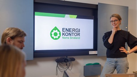 Energikontorets logga på en skärm med en person som står framför och presenterar.