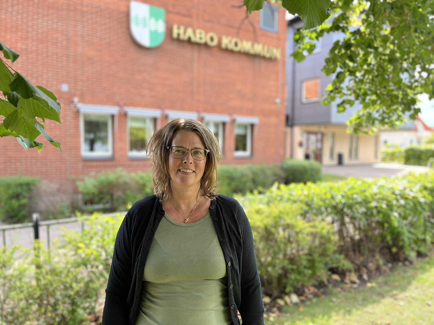 En bild på Anna Lööv utanför Habo Kommuns kontor en solig vårdag