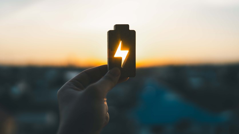 Hand som håller i batteri mot soluppgång