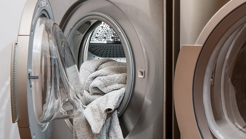 Silverfärgad tvättmaskin med grå handduk i.