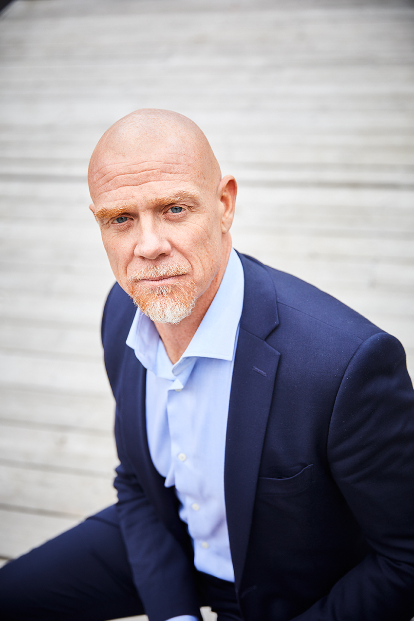 Robert har kostym och rakat huvud.