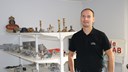 På bilden syns David Stenberg, delägare i Reftele gjuteri. Han står framför en hylla med mängder av produkter som de har gjutit.