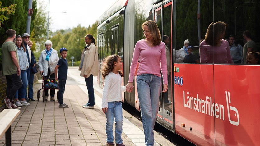 Person håller sitt barn i handen och går från bussen tillsammans. 