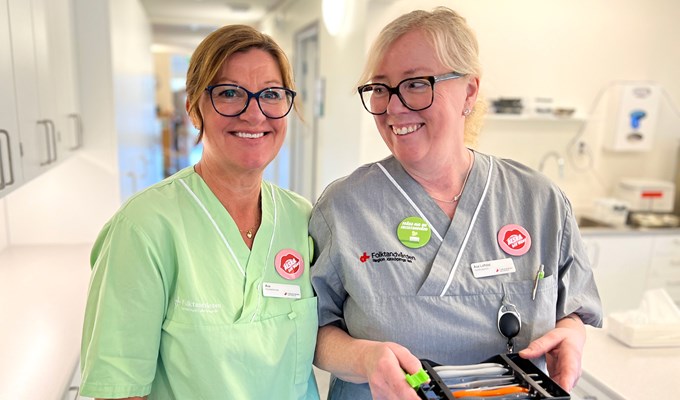 Två kvinnor i klinikkläder skrattar och kollar in i kameran.