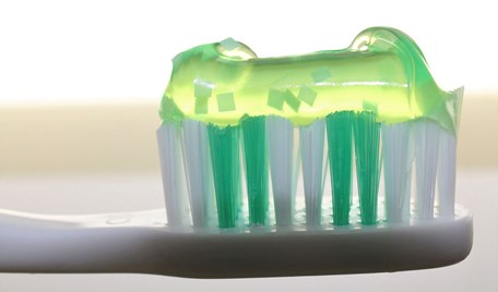 Ett tandborshuvud i närbild. Ovanpå tandborsthuvudet ligger det grön genomskinlig tandkräm