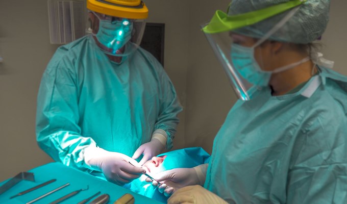 Två behandlare opererar en patient.