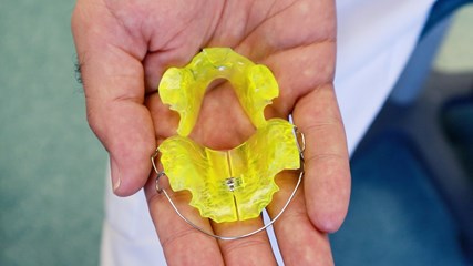 En öppen hand som håller en neongrön tandställning.