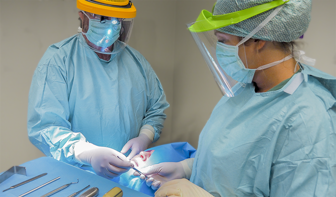Två tandläkare opererar en patient