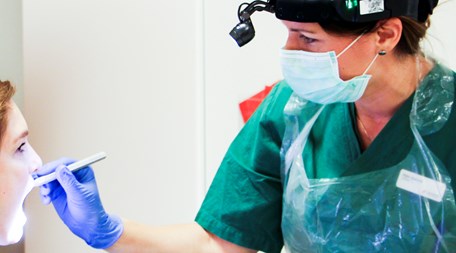 En behandlare tittar in i munnen på en patient.