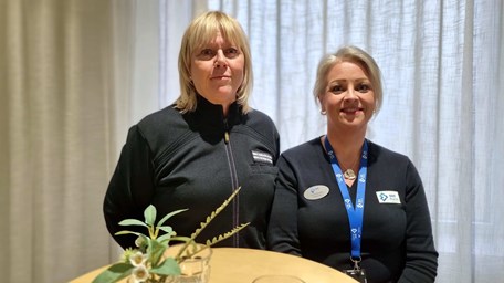 Två kvinnor står bakom ett bord. 