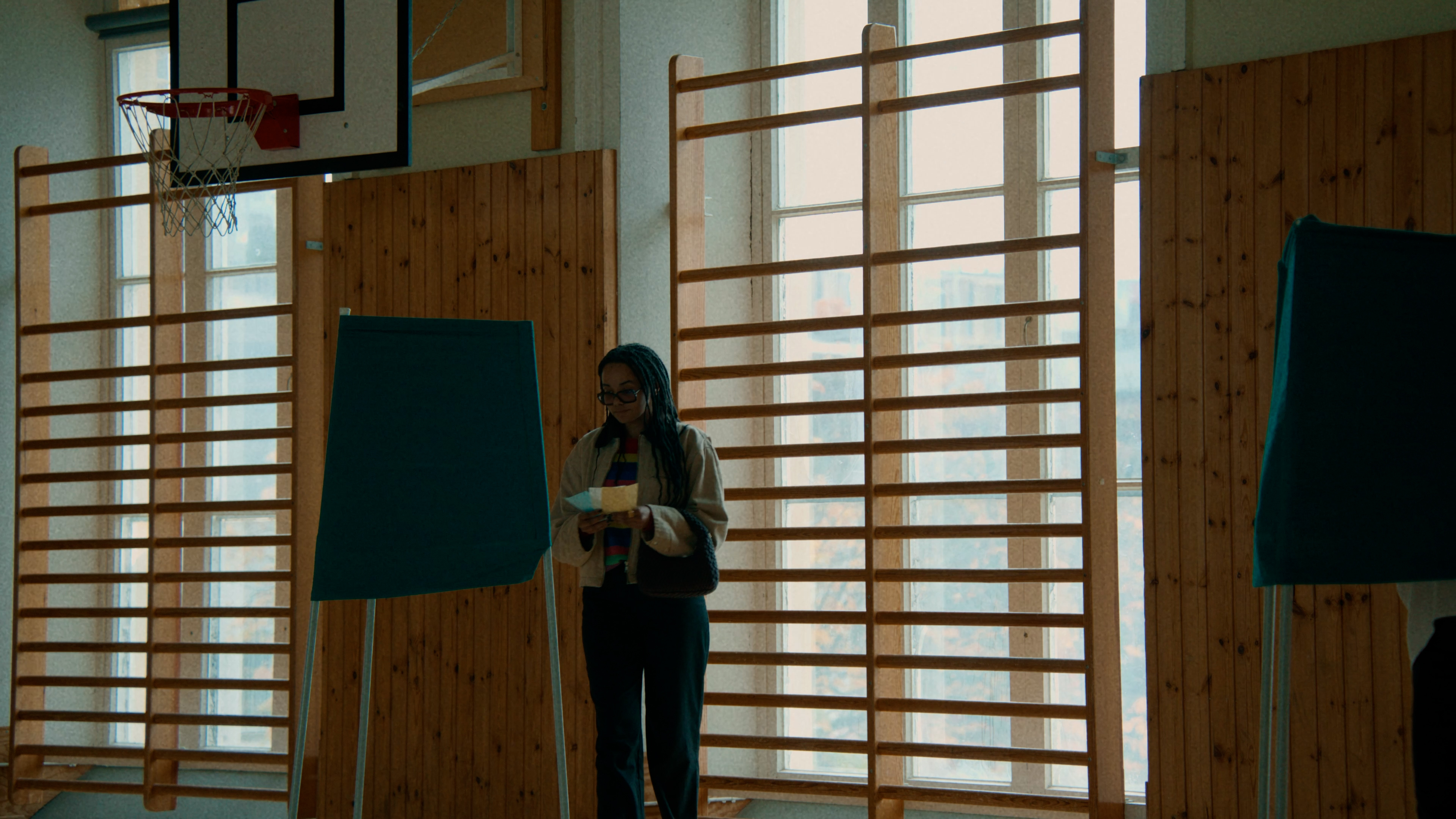 En person håller i valsedlar vid ett valbås. 