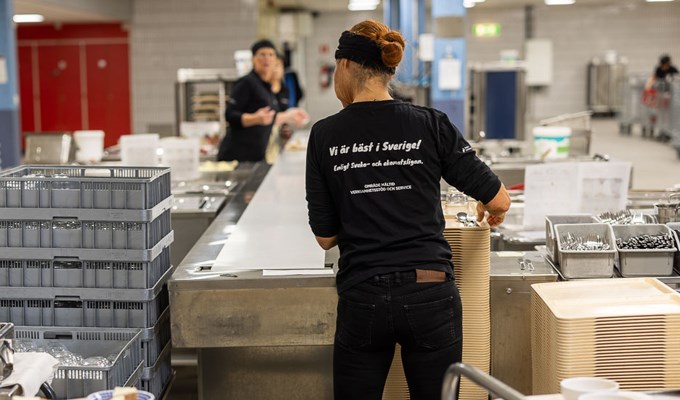 Kvinnlig medarbetare i produktionskök. På ryggen på hennes tröja står det Vi är bäst i Sverige...