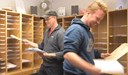 Två killar sorterar post i postfack.