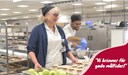 Glada medarbetare, en kvinna och en man, i produktionsköket. I bilden är texten "Vi brinner för goda måltider!" inlagd.