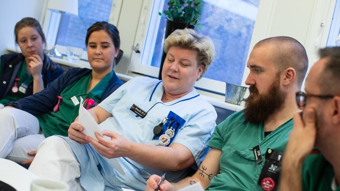 En chef sitter i en soffa med två medarbetare på varje sida om sig.