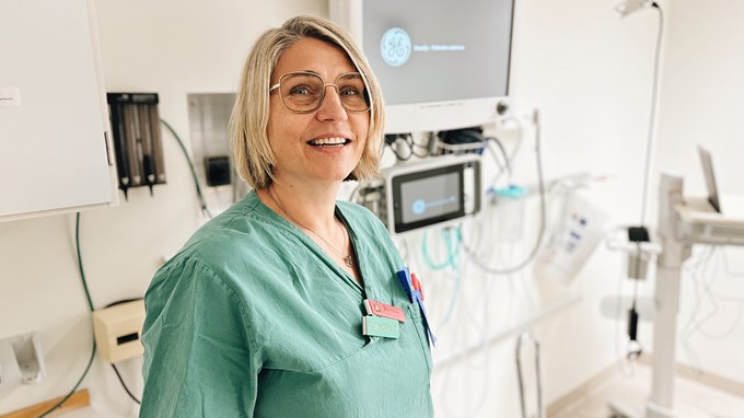 Vårdpersonal som är arbetsklädd och ler mot kameran. 