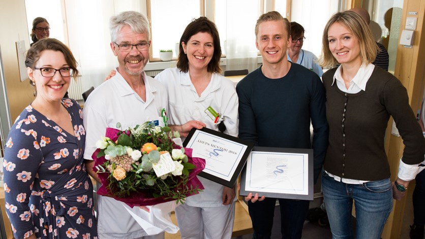 Fem personer står tillsammans och håller upp blommor och diplom