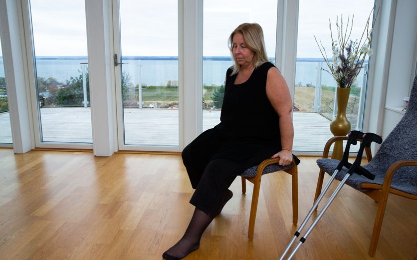 En kvinna sitter på en pall och böjer sitt nyopererade knä