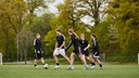 Fem ungdomar som spelar fotboll ihop. 