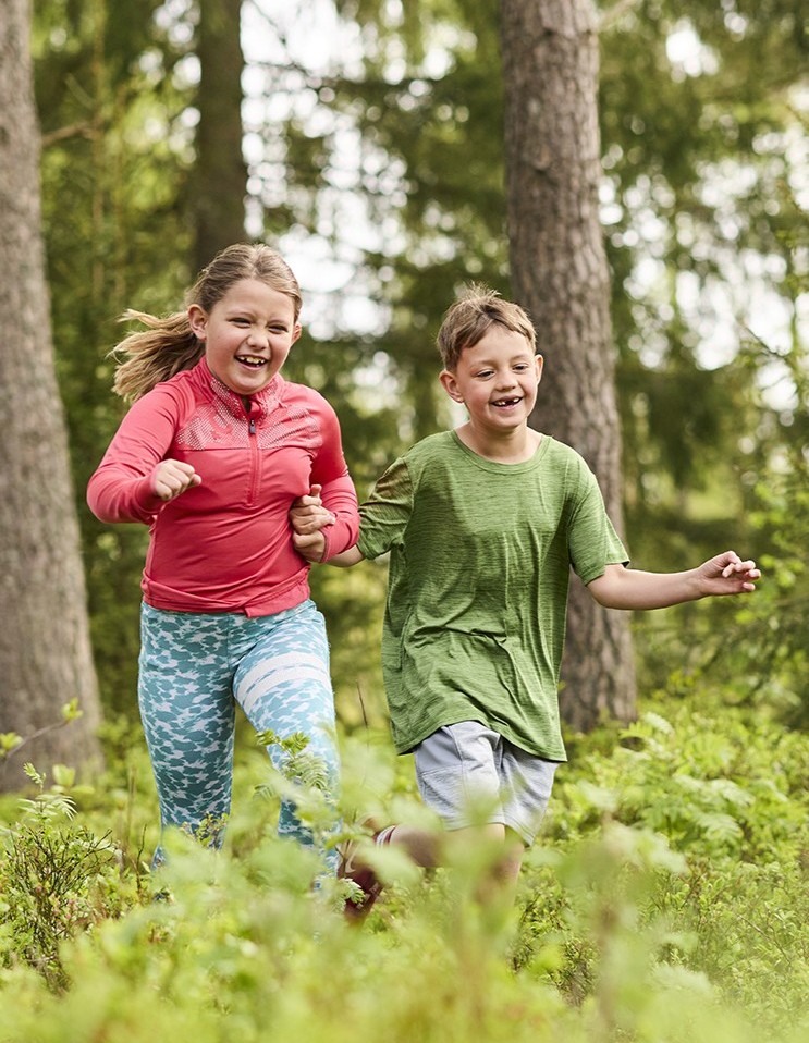 Två barn som leker i skogen.