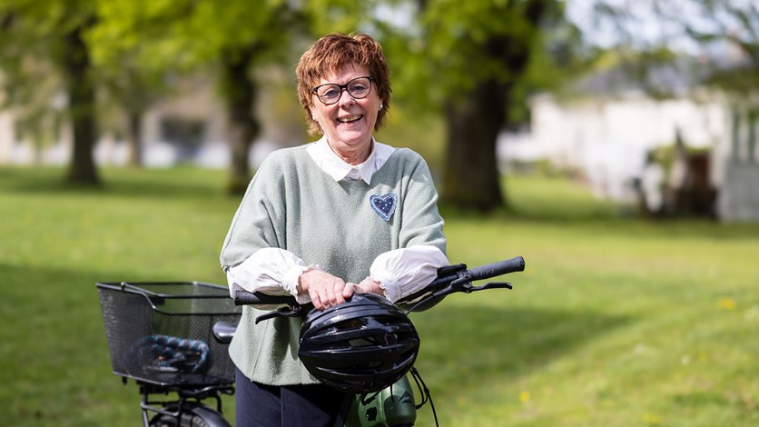 Carina Eldåker står med sin cykel och skrattar mot kameran. 