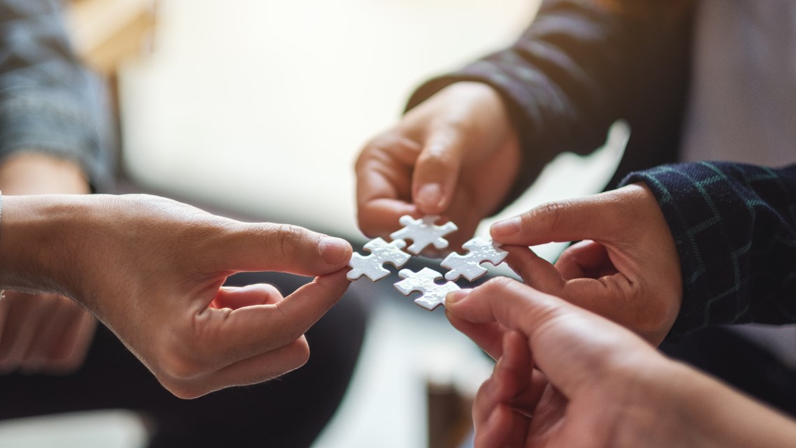 Fyra små pusselbitar hålls mot varandra. 