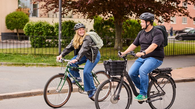 Två personer cyklar genom staden. 