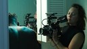 En ung kvinna bakom en filmkamera. 