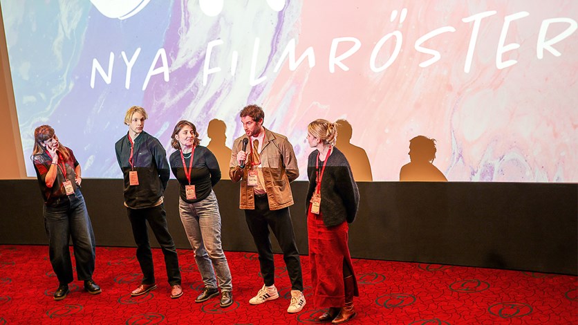 Människor samtalar framför en biografduk. 