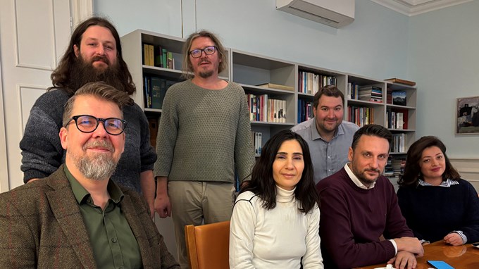 Människor som sitter och står runt ett bord.  