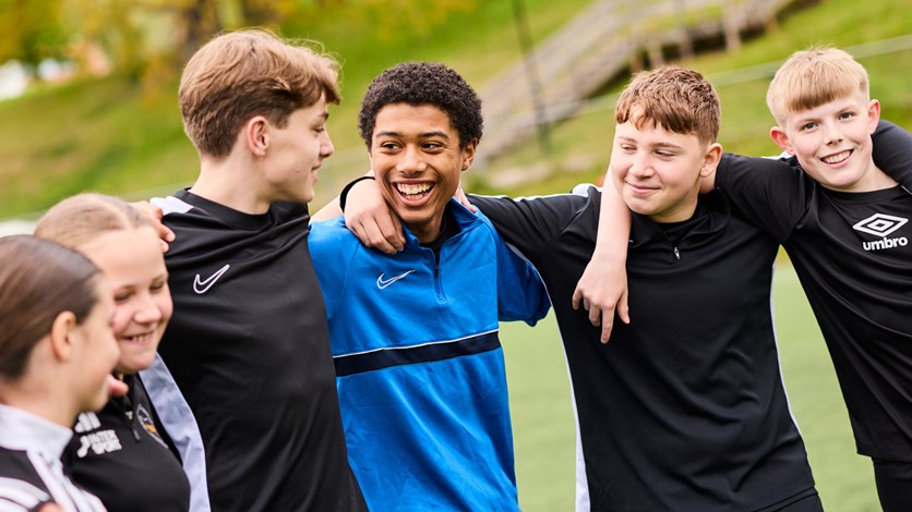 Unga fotbollskillar håller varandra om axlarna. 