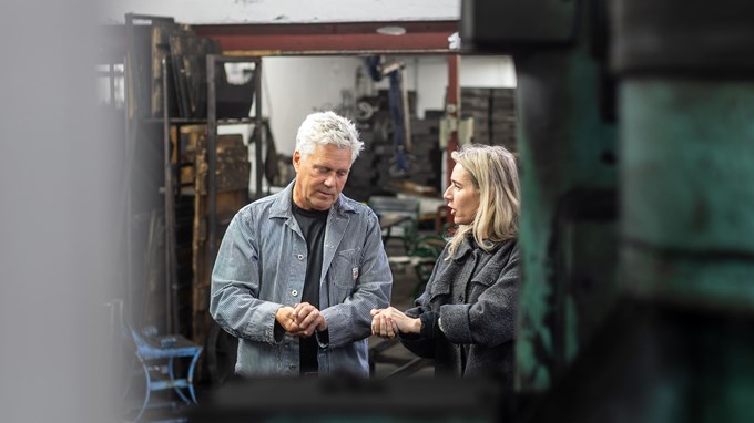 En man och en kvinna står på en industri och samtalar. 