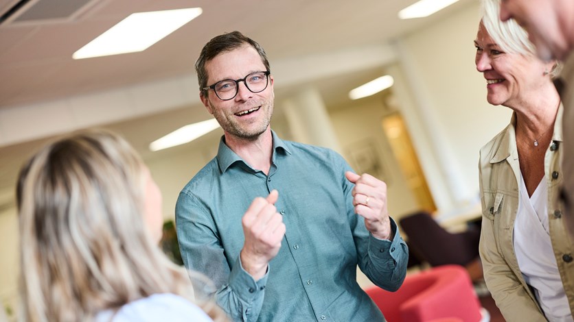 Medelålders glad man pratar med kollegor.
