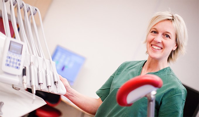 En tandsköterska som står framför en tandläkarstol