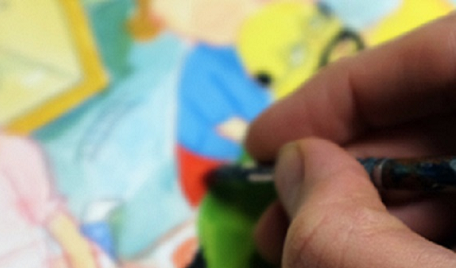 Hand som målar på en färgglad illustration.
