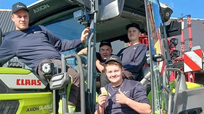 Stora Segerstadsgymnasiets lag i traktor-SM sitter på en grön traktor och ler mot kameran.
