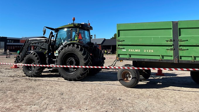 En svart traktor med ett grönt släp.